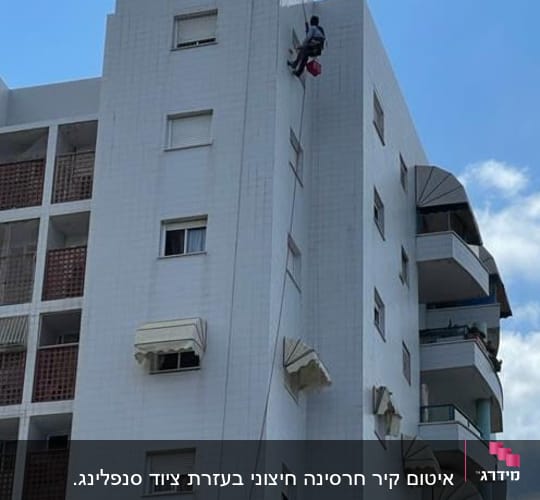 אדם תלוי על חבל מבצע עבודות גובה על בניין